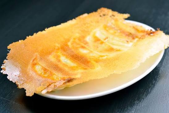 皿に盛られた羽根つき餃子。羽根の部分が金色に美しく焼き上がっている